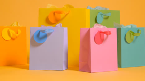 Studio-Shot-Of-Colourful-Birthday-Party-Gift-Bags-Against-Yellow-Background-1